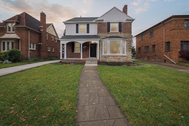 view of property featuring covered porch and a lawn