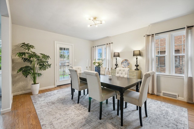 dining room with light wood-type flooring and an inviting chandelier