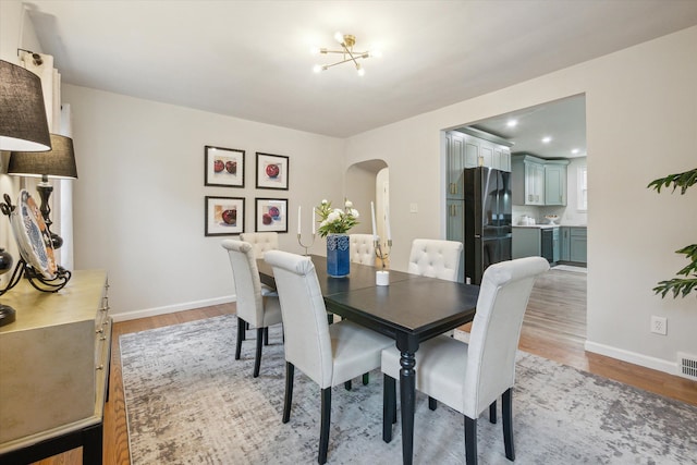 dining space featuring light wood-type flooring and a notable chandelier