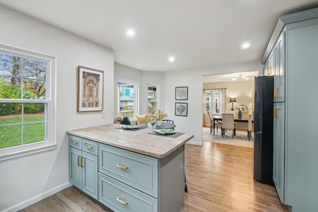 kitchen featuring kitchen peninsula, light wood-type flooring, a wealth of natural light, and black refrigerator