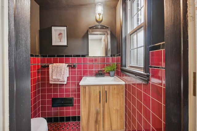 bathroom with vanity, toilet, and tile walls