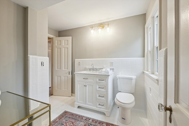 bathroom with tile patterned floors, vanity, toilet, and tile walls