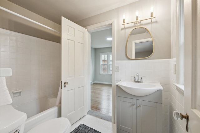 full bathroom featuring vanity, hardwood / wood-style flooring, tile walls, toilet, and tiled shower / bath