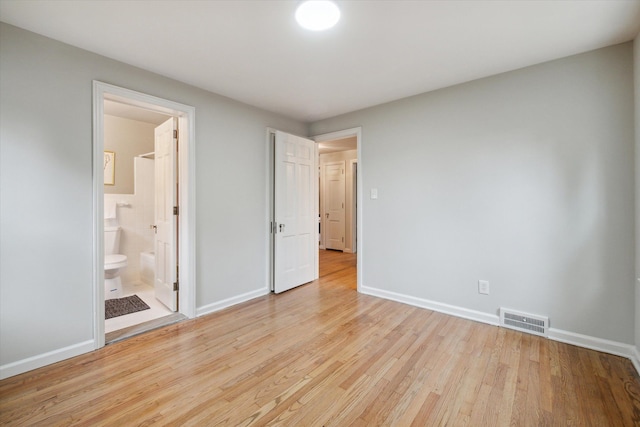 unfurnished bedroom featuring ensuite bath and light hardwood / wood-style flooring