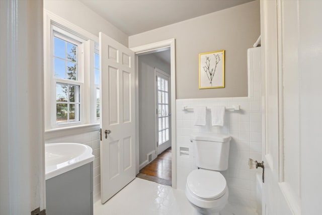 bathroom with tile patterned floors, vanity, toilet, and tile walls