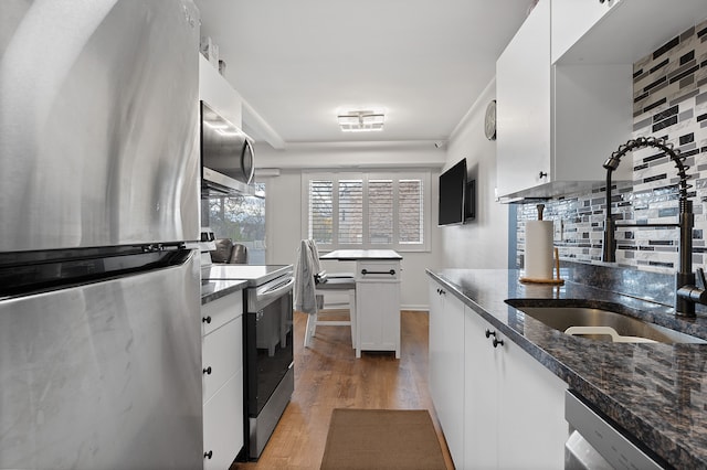 kitchen featuring white cabinets, sink, light hardwood / wood-style flooring, decorative backsplash, and appliances with stainless steel finishes