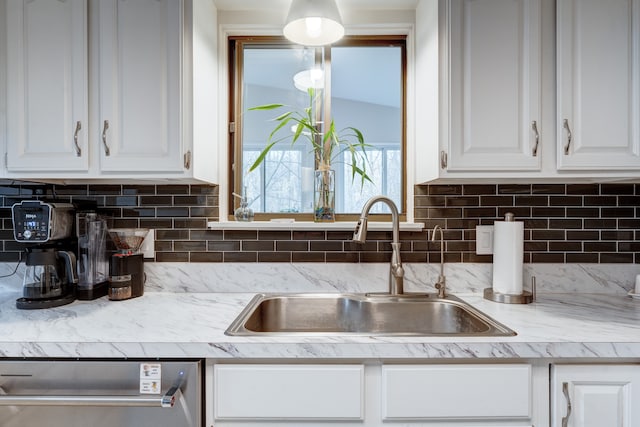 kitchen featuring tasteful backsplash, sink, stainless steel dishwasher, and white cabinets