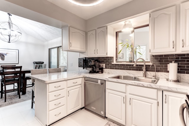 kitchen featuring sink, white cabinetry, decorative light fixtures, stainless steel dishwasher, and kitchen peninsula