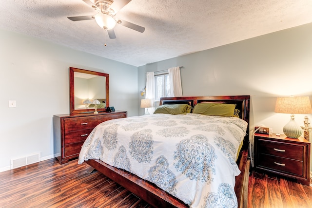 bedroom with dark wood-type flooring, a textured ceiling, and ceiling fan