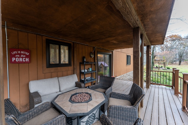 wooden terrace featuring a porch and a fire pit