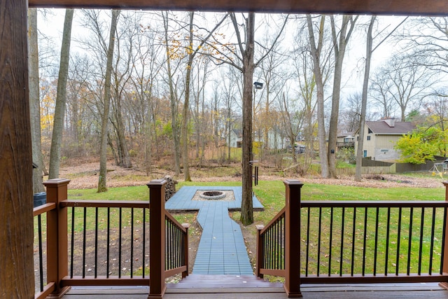 wooden deck with a lawn and an outdoor fire pit