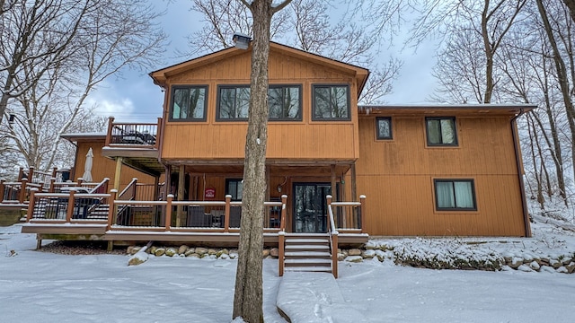 snow covered rear of property featuring a balcony