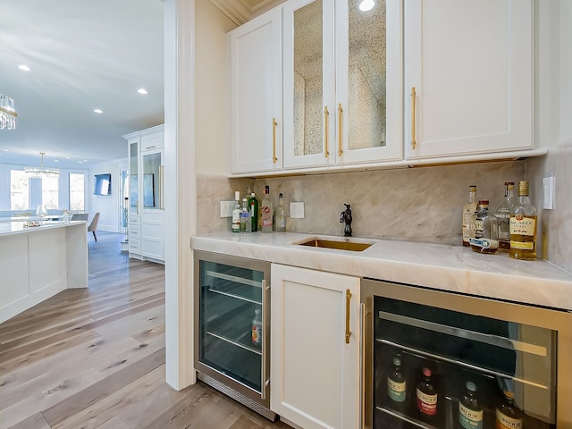 bar featuring white cabinetry, sink, beverage cooler, and light hardwood / wood-style flooring