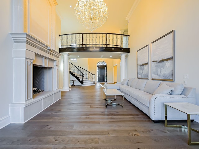 living room featuring hardwood / wood-style flooring, a notable chandelier, a towering ceiling, and crown molding