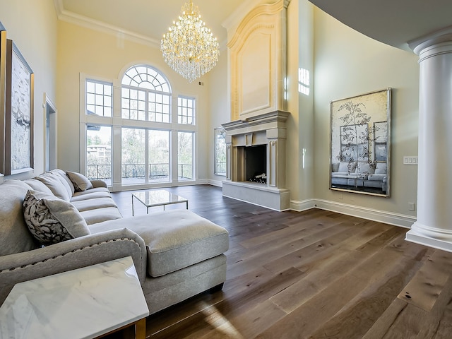 living room with a towering ceiling, dark hardwood / wood-style flooring, ornamental molding, and a notable chandelier