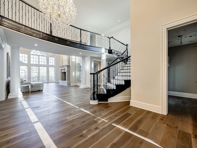 foyer entrance featuring hardwood / wood-style flooring, a towering ceiling, crown molding, and an inviting chandelier