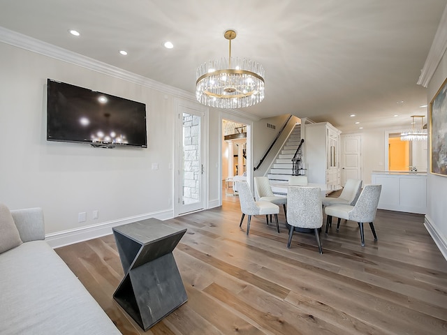 dining area with hardwood / wood-style flooring, an inviting chandelier, and ornamental molding