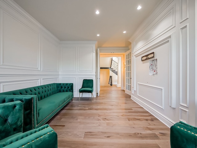 living area with light hardwood / wood-style floors and crown molding