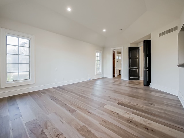 empty room with light wood-type flooring, a wealth of natural light, and vaulted ceiling