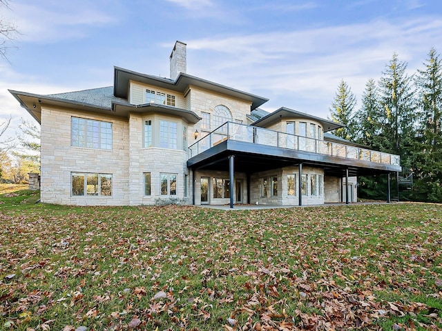 back of house featuring a lawn and a balcony