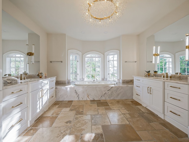 bathroom with vanity, a relaxing tiled tub, and an inviting chandelier