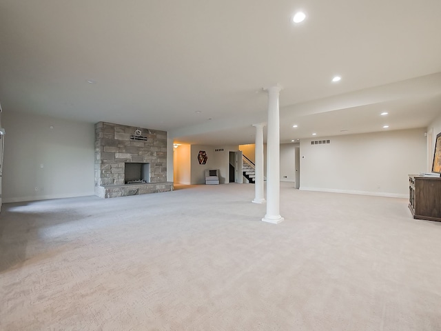 unfurnished living room featuring light carpet, decorative columns, and a stone fireplace