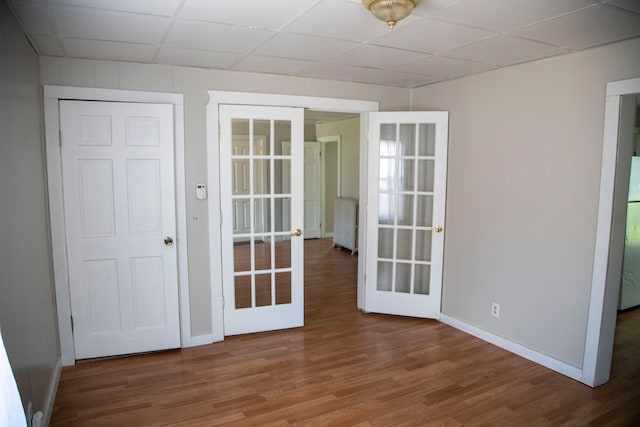 unfurnished room featuring french doors, wood-type flooring, and a drop ceiling