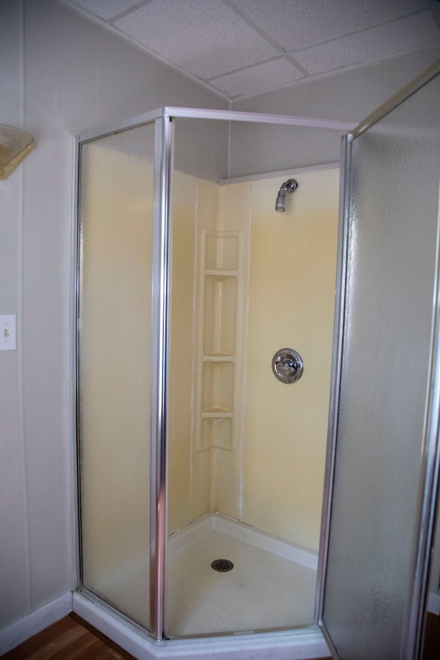 bathroom featuring hardwood / wood-style floors, a paneled ceiling, and walk in shower