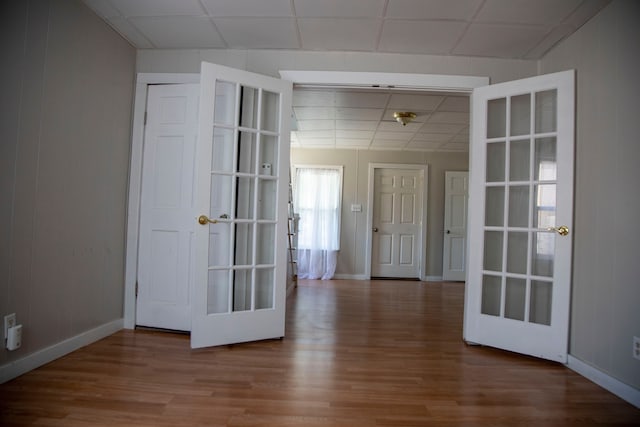 spare room with a paneled ceiling, hardwood / wood-style floors, and french doors