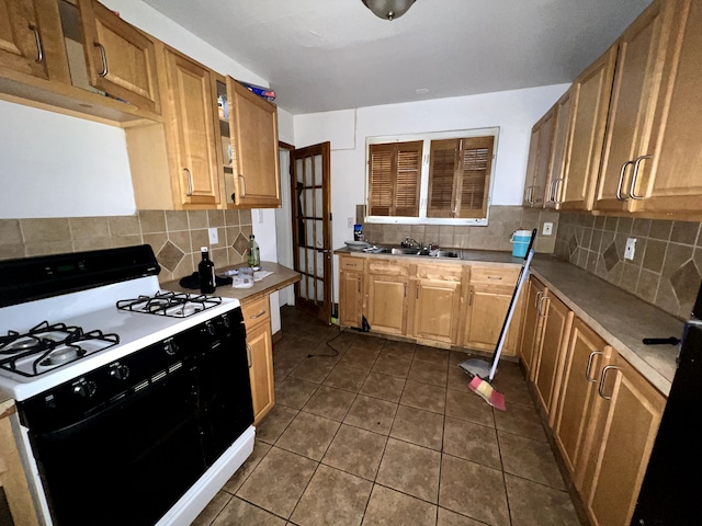 kitchen featuring tasteful backsplash, sink, dark tile patterned floors, and white gas range oven