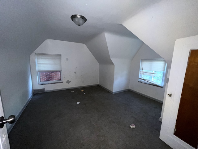 additional living space featuring dark colored carpet and lofted ceiling