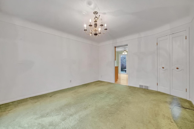 spare room with carpet flooring and an inviting chandelier