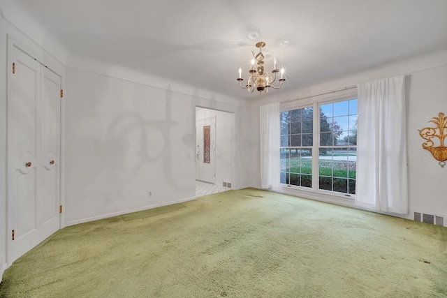 carpeted spare room with an inviting chandelier