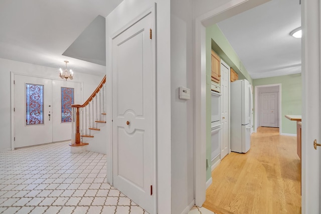 hallway featuring light hardwood / wood-style flooring, a chandelier, and french doors