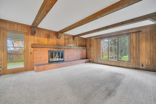 unfurnished living room featuring wood walls, plenty of natural light, carpet, and a brick fireplace