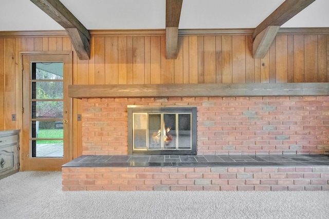 room details with beamed ceiling, carpet floors, a brick fireplace, and wood walls