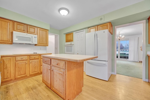 kitchen with a chandelier, white appliances, a center island, and light hardwood / wood-style floors