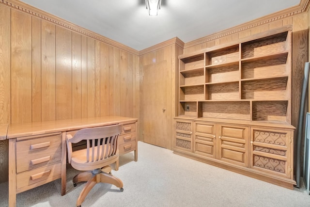 office with wood walls, built in desk, and light carpet