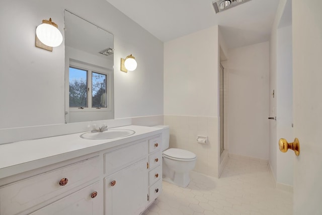 bathroom featuring vanity, tile patterned floors, toilet, walk in shower, and tile walls