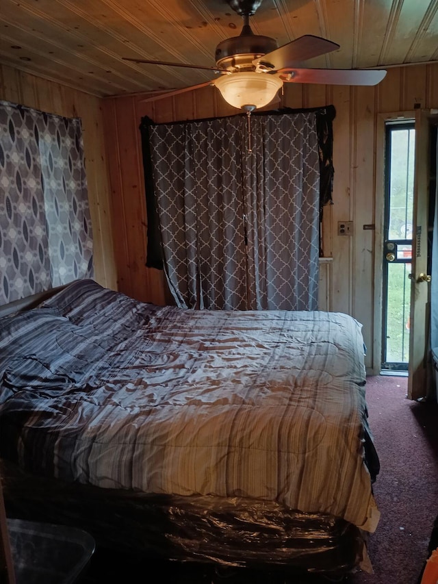 carpeted bedroom with ceiling fan, wood ceiling, and wood walls