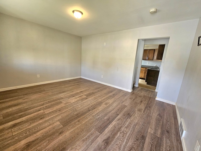 unfurnished room featuring sink and dark wood-type flooring