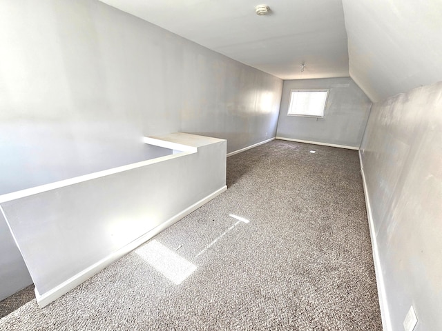 additional living space featuring dark colored carpet and vaulted ceiling