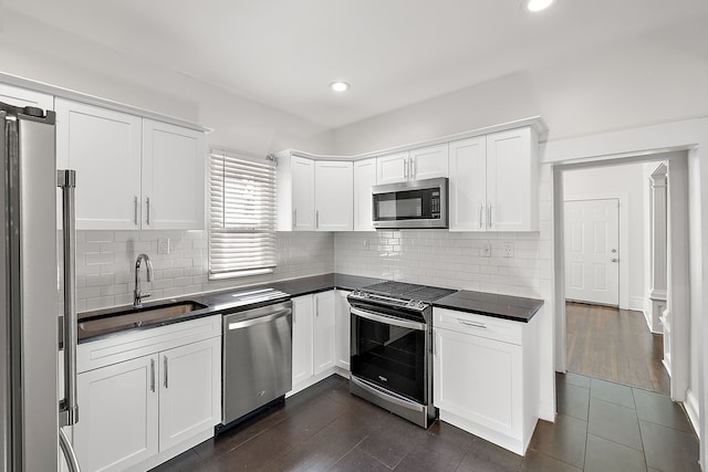 kitchen with dark wood-type flooring, sink, tasteful backsplash, white cabinetry, and stainless steel appliances