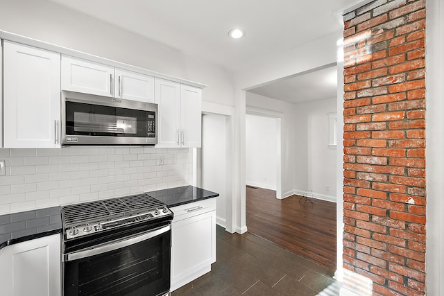 kitchen featuring white cabinets, backsplash, dark wood-type flooring, and appliances with stainless steel finishes