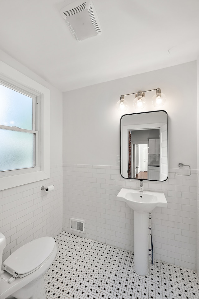 bathroom featuring tile patterned floors, tile walls, and toilet