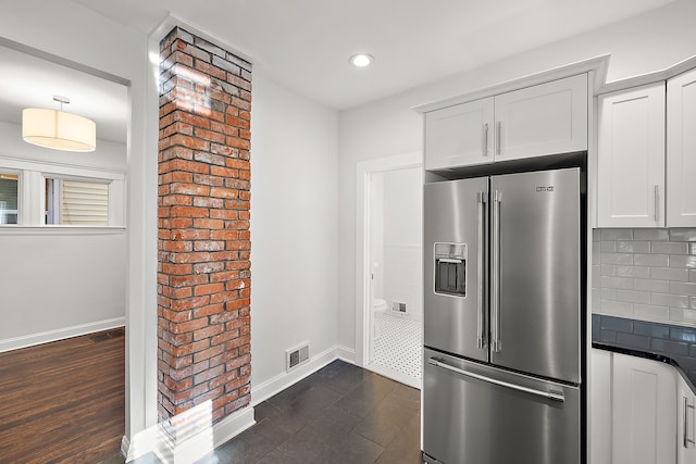 kitchen featuring white cabinets, stainless steel refrigerator with ice dispenser, dark hardwood / wood-style flooring, and decorative backsplash