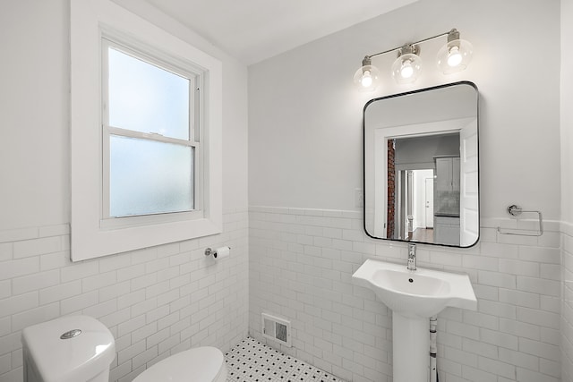 bathroom with toilet and tile walls