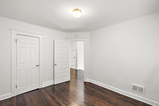 unfurnished bedroom with dark wood-type flooring and a closet