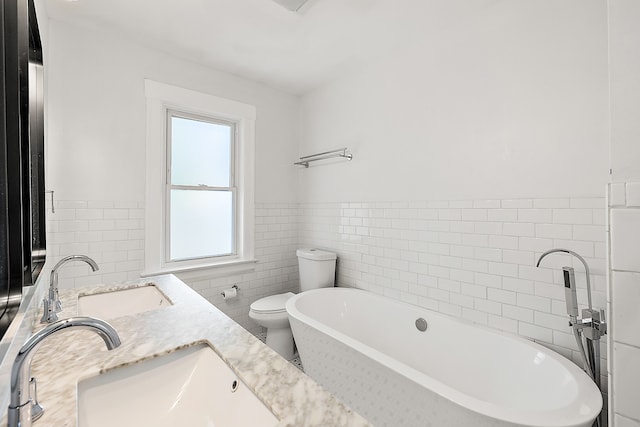 bathroom featuring vanity, a bathtub, toilet, and tile walls