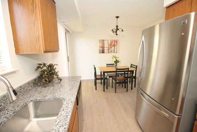 40831 Highpointe Dr, Clinton Township, MI 48038 - kitchen featuring freestanding refrigerator, a sink, brown cabinets, light wood-type flooring, and light stone countertops